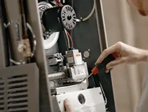Furnace repair technician inspecting internal components and wiring in Knoxville, TN