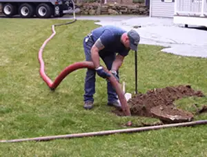 Septic pumping technician servicing a residential septic tank with a vacuum hose in Knoxville, TN
