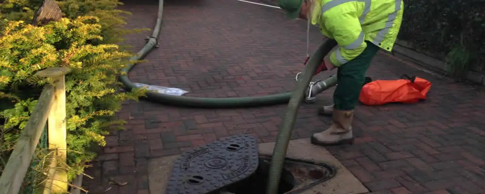 Septic tank cleaning technician servicing a septic tank with a vacuum hose in Knoxville, TN