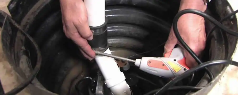 Sump pump installation technician connecting PVC discharge piping in Knoxville, TN
